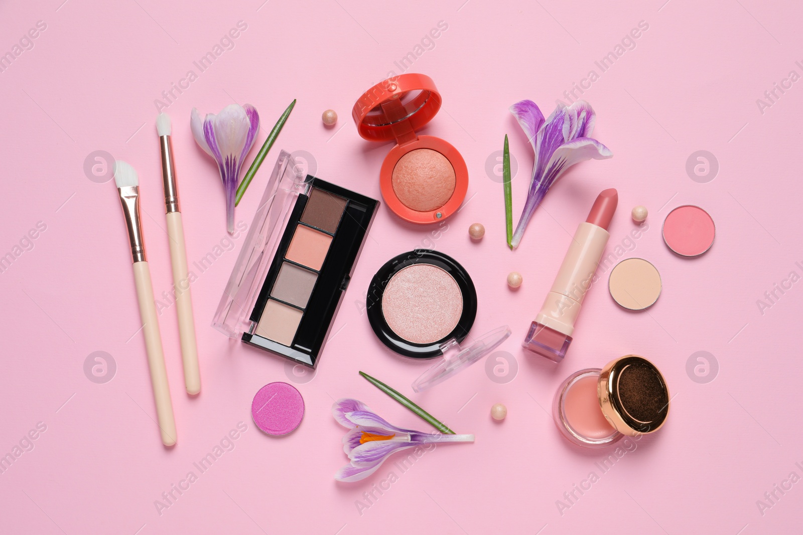 Photo of Flat lay composition with different makeup products and beautiful flowers on pink background