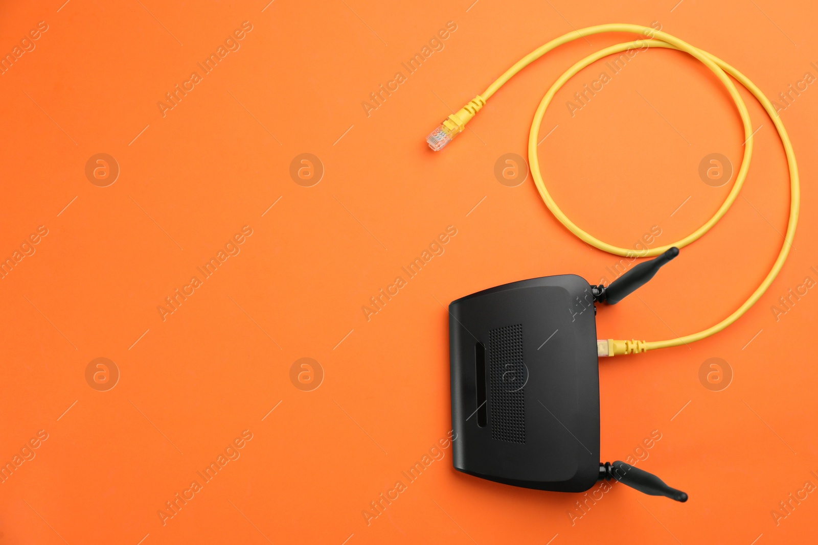 Photo of Modern Wi-Fi router on orange background, top view. Space for text