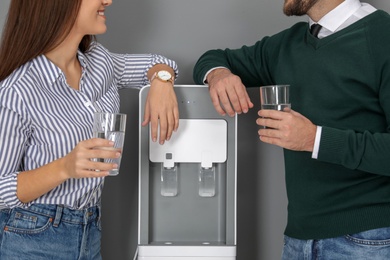 Employees with glasses near water cooler in office