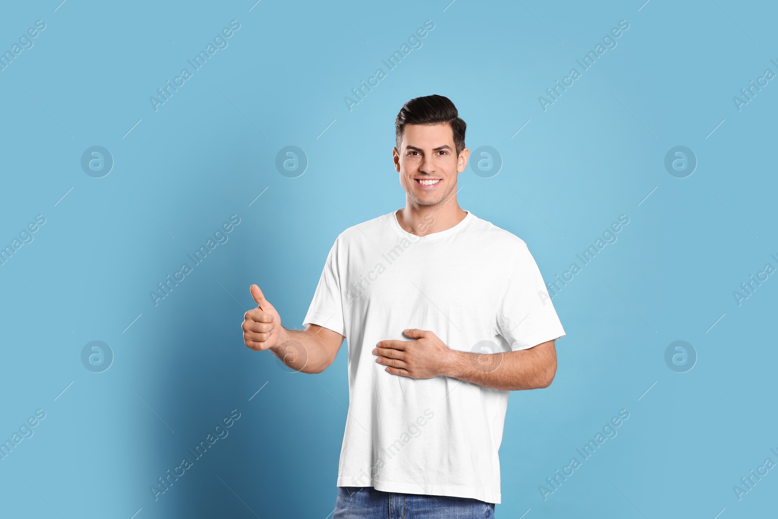 Photo of Happy healthy man touching his belly on light blue background