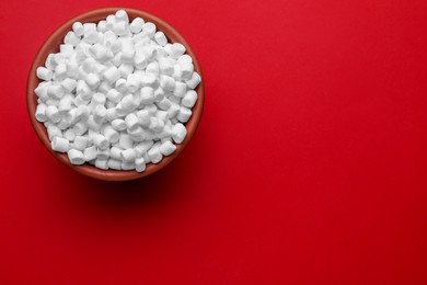 Photo of Bowl with delicious marshmallows on red background, top view. Space for text