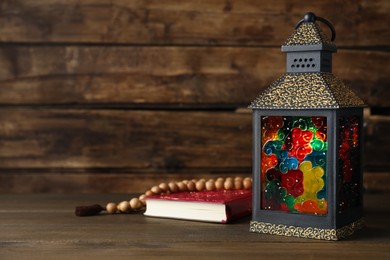 Photo of Decorative Arabic lantern, Quran and prayer beads on wooden table. Space for text