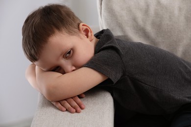 Photo of Sad little boy on sofa at home