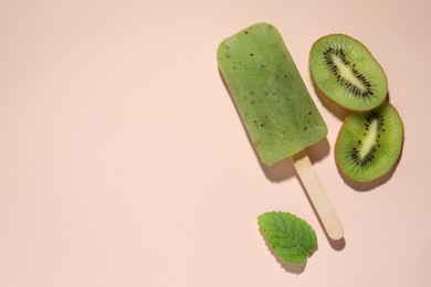 Photo of Tasty kiwi ice pop and space for text on pale light pink background, top view. Fruit popsicle