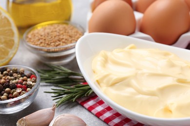 Photo of Delicious homemade mayonnaise, spices and ingredients on grey table, closeup