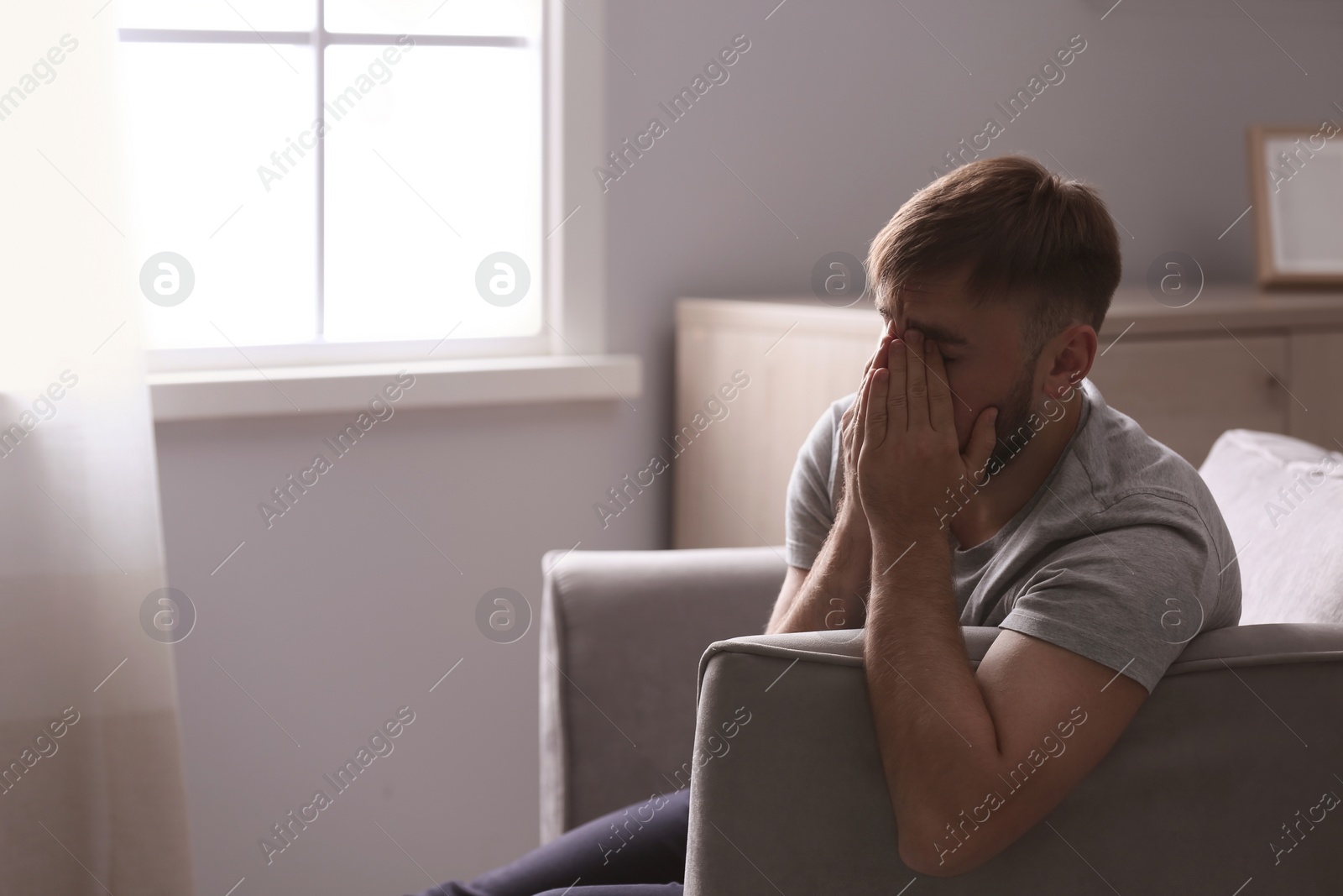 Photo of Depressed young man sitting in armchair at home