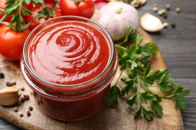 Photo of Tasty ketchup, fresh tomatoes, parsley and spices on grey wooden table