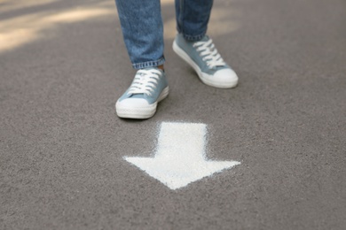 Person standing near arrow on asphalt, closeup