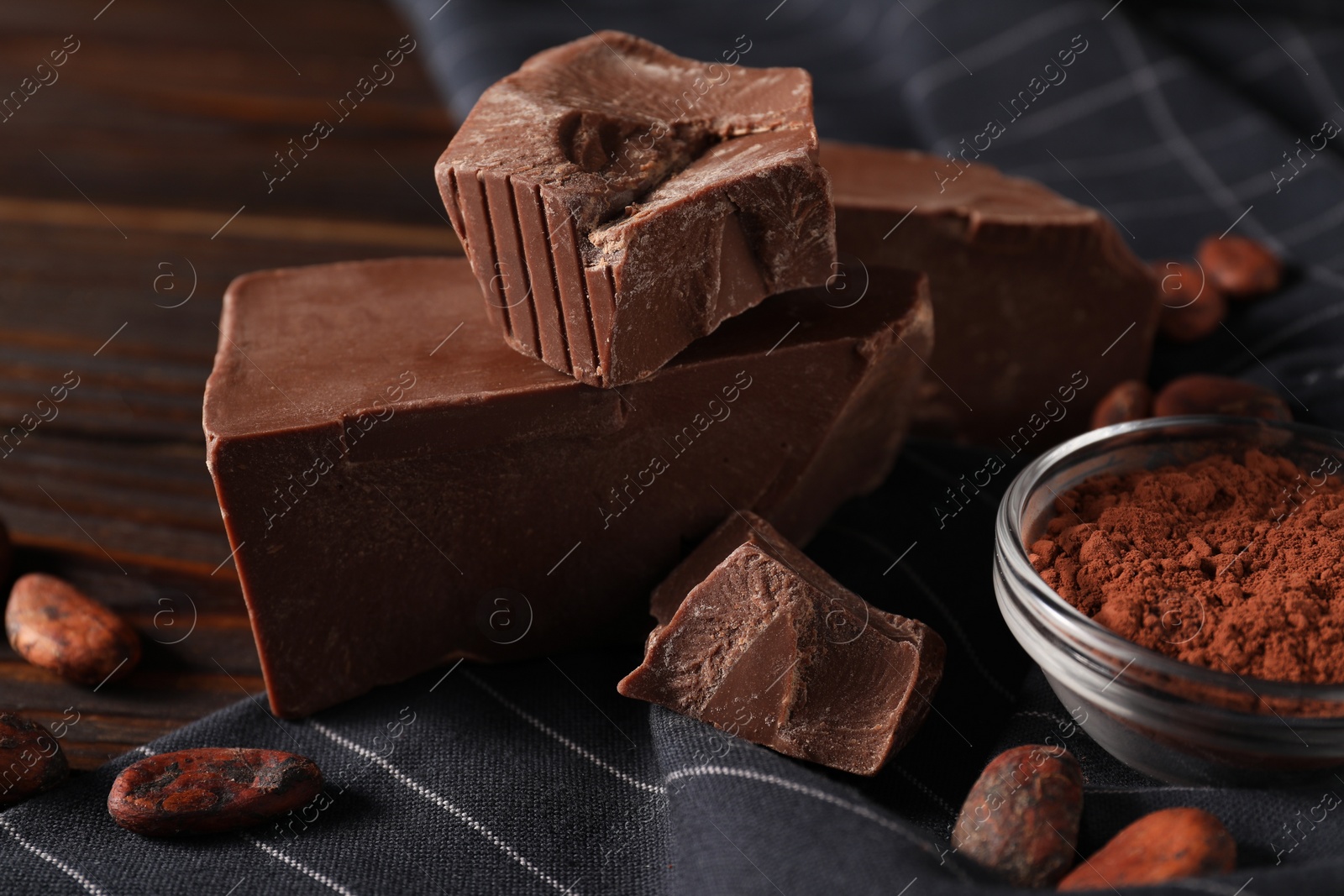 Photo of Pieces of tasty milk chocolate and cocoa beans on table, closeup