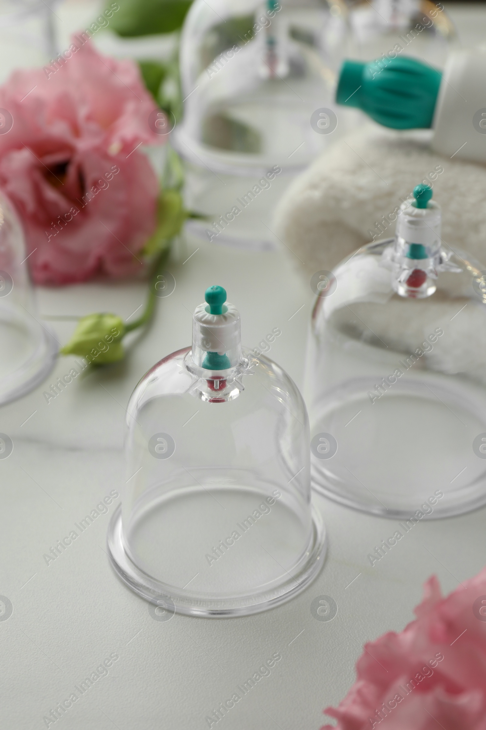 Photo of Plastic cups and flowers on white marble table. Cupping therapy