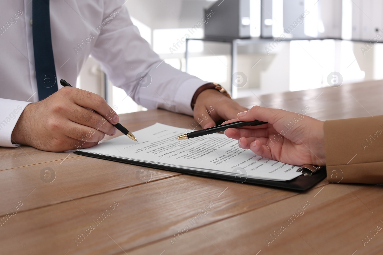 Photo of Businesspeople working with contract at wooden table indoors, closeup