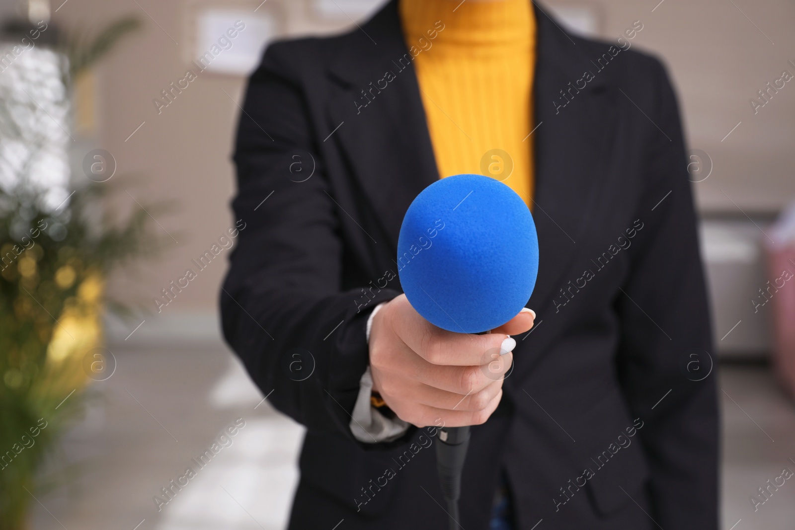 Photo of Professional journalist with modern microphone in room, closeup