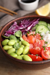 Photo of Poke bowl with salmon, edamame beans and vegetables on wooden table, closeup