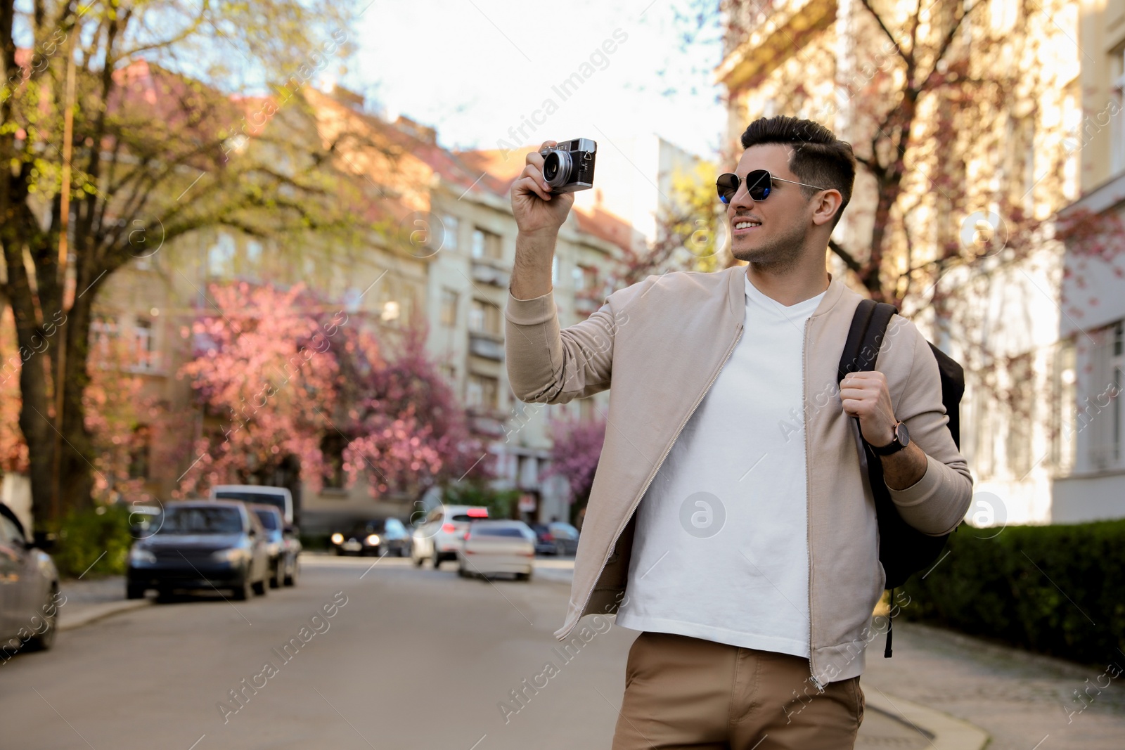 Photo of Happy male tourist with camera on city street