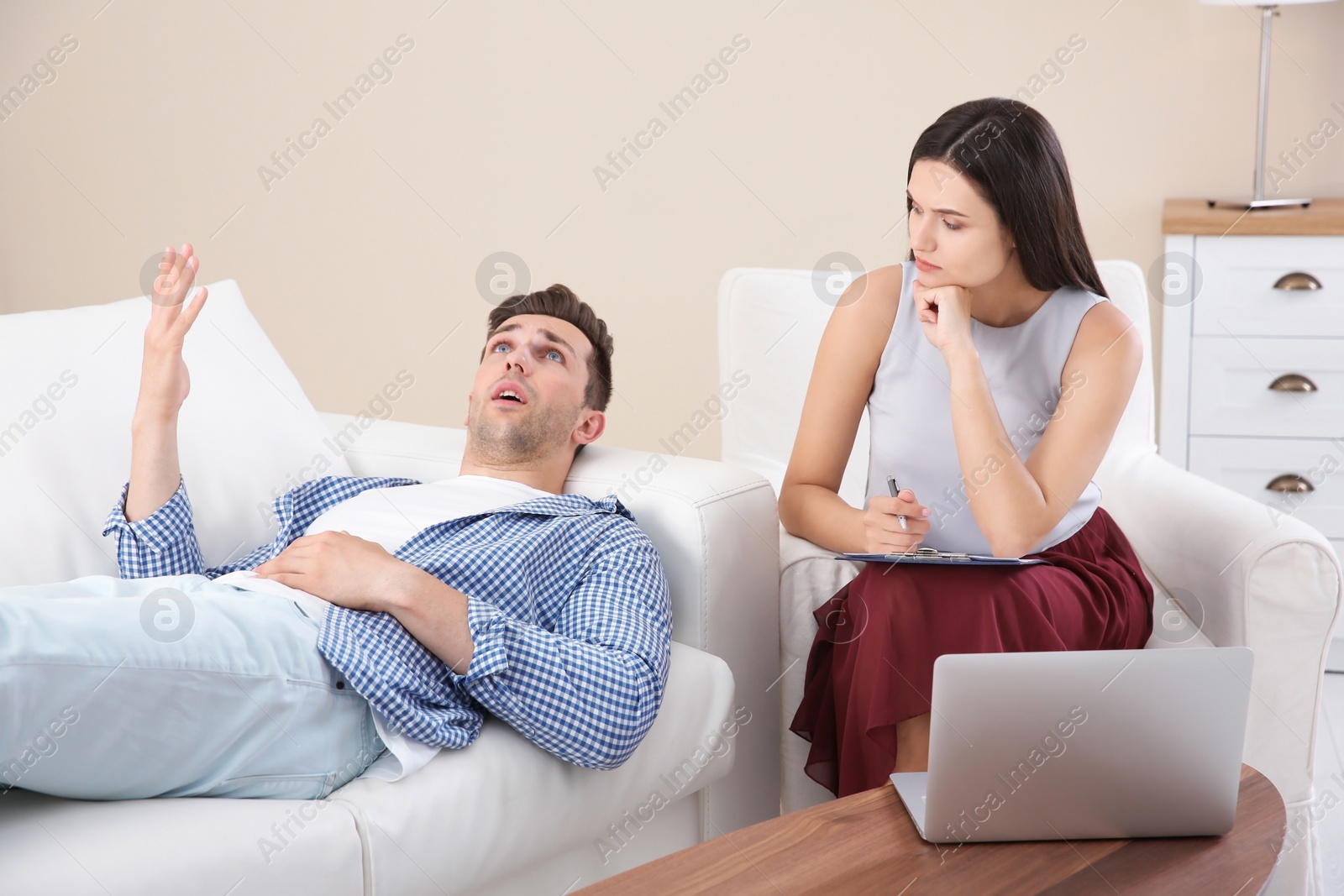 Photo of Depressed young man having appointment with psychologist in office