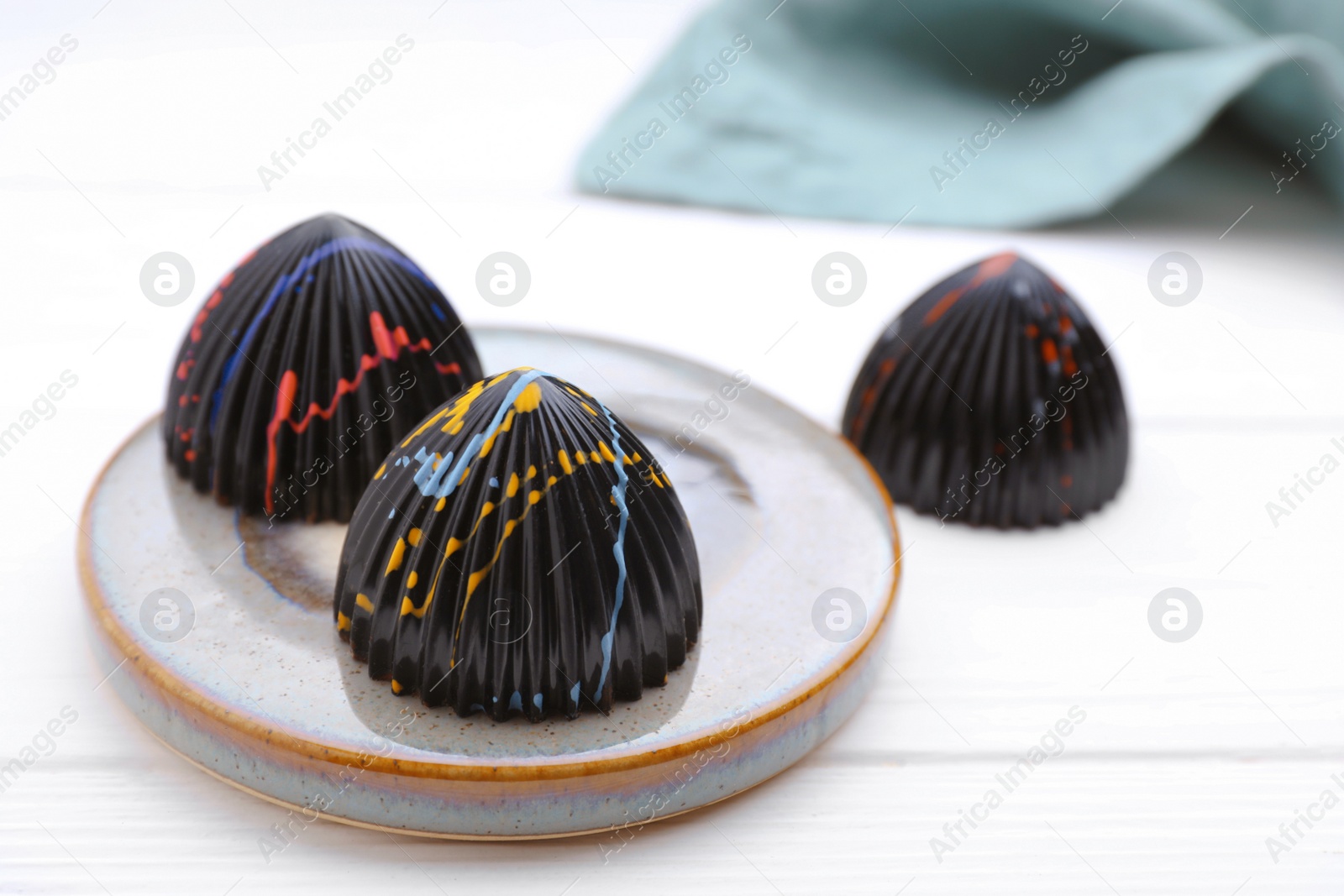 Photo of Tasty chocolate candies on white wooden table, closeup