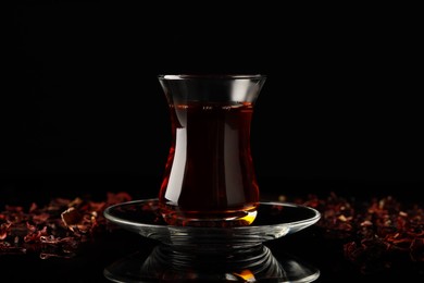 Photo of Glass of traditional Turkish tea on black table
