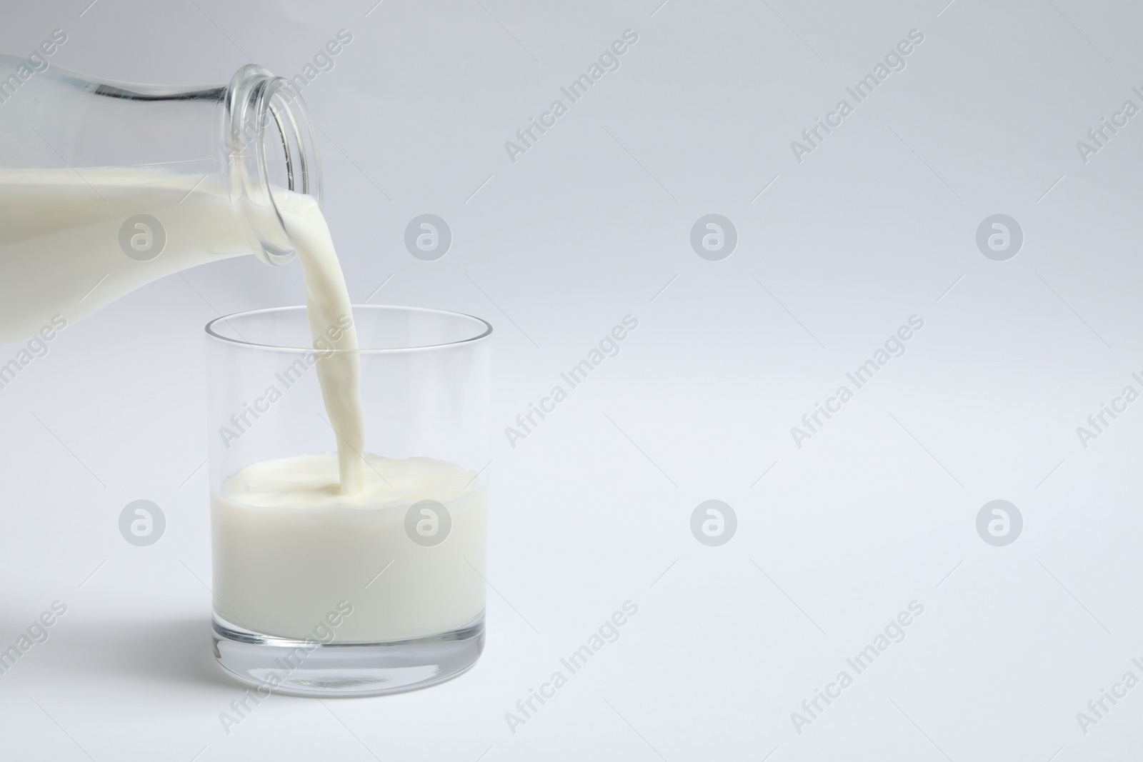 Photo of Pouring milk into glass on white background
