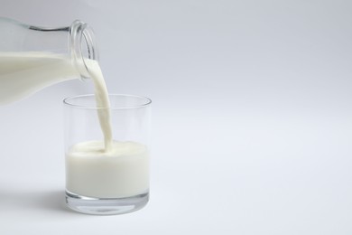 Pouring milk into glass on white background