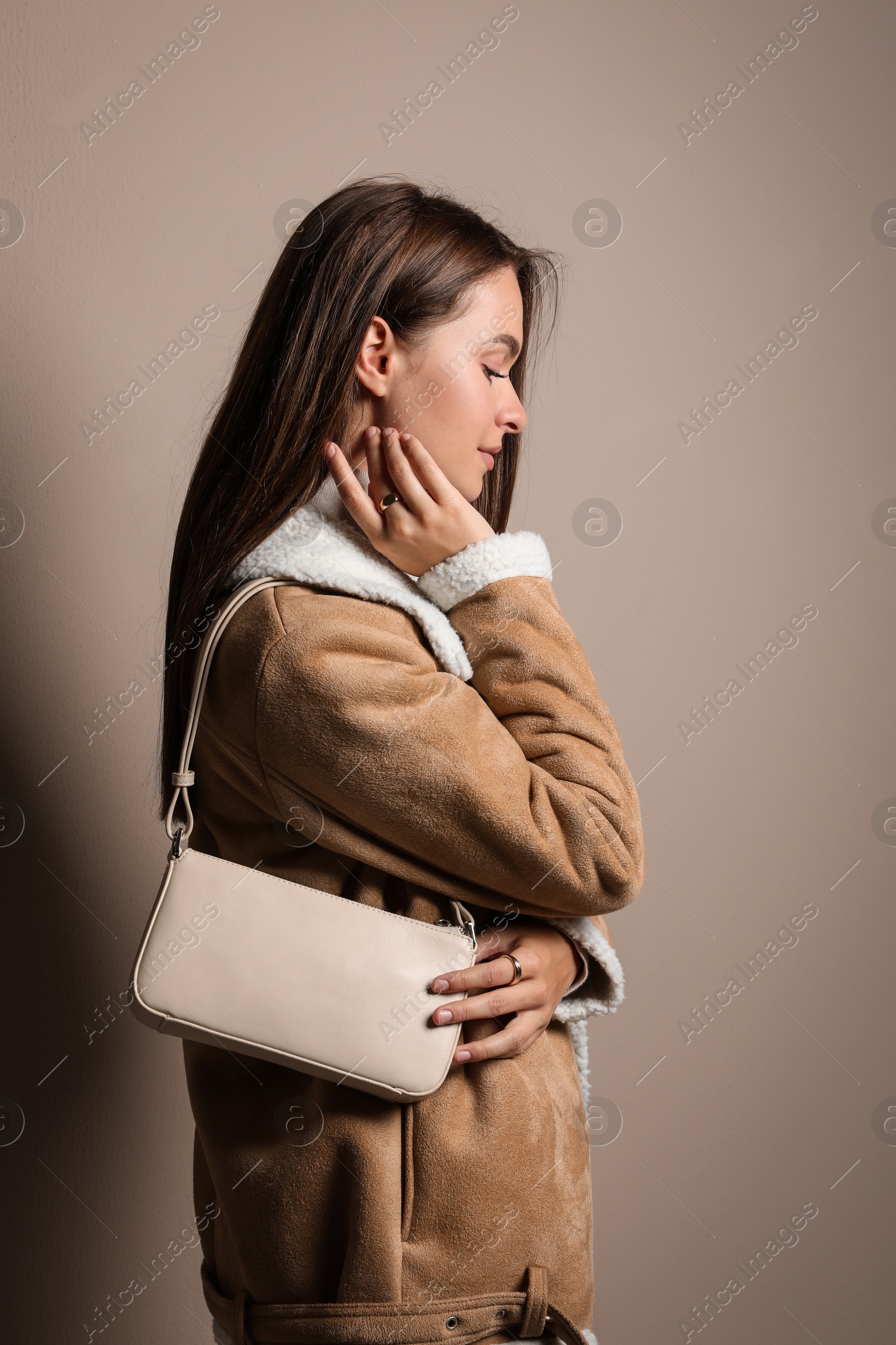 Photo of Fashionable young woman with stylish bag on beige background