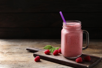 Yummy raspberry smoothie in mason jar on wooden table. Space for text