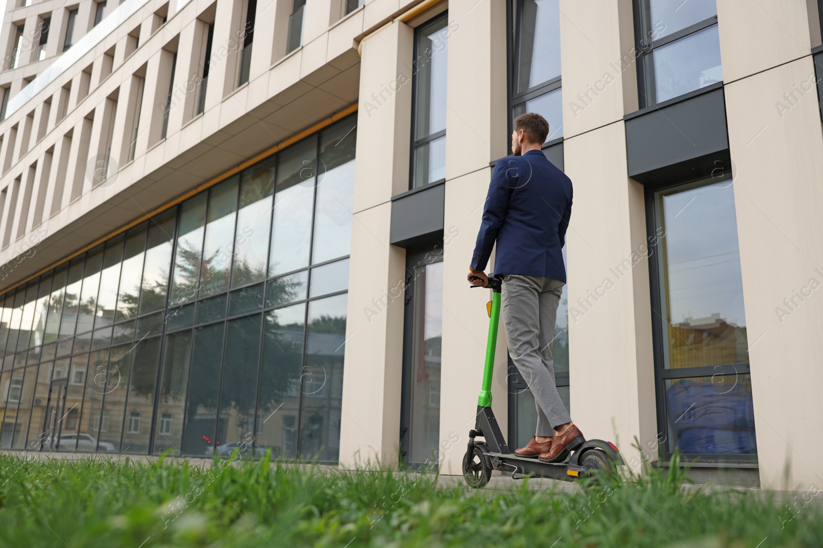 Photo of Businessman riding modern kick scooter on city street, back view. Space for text