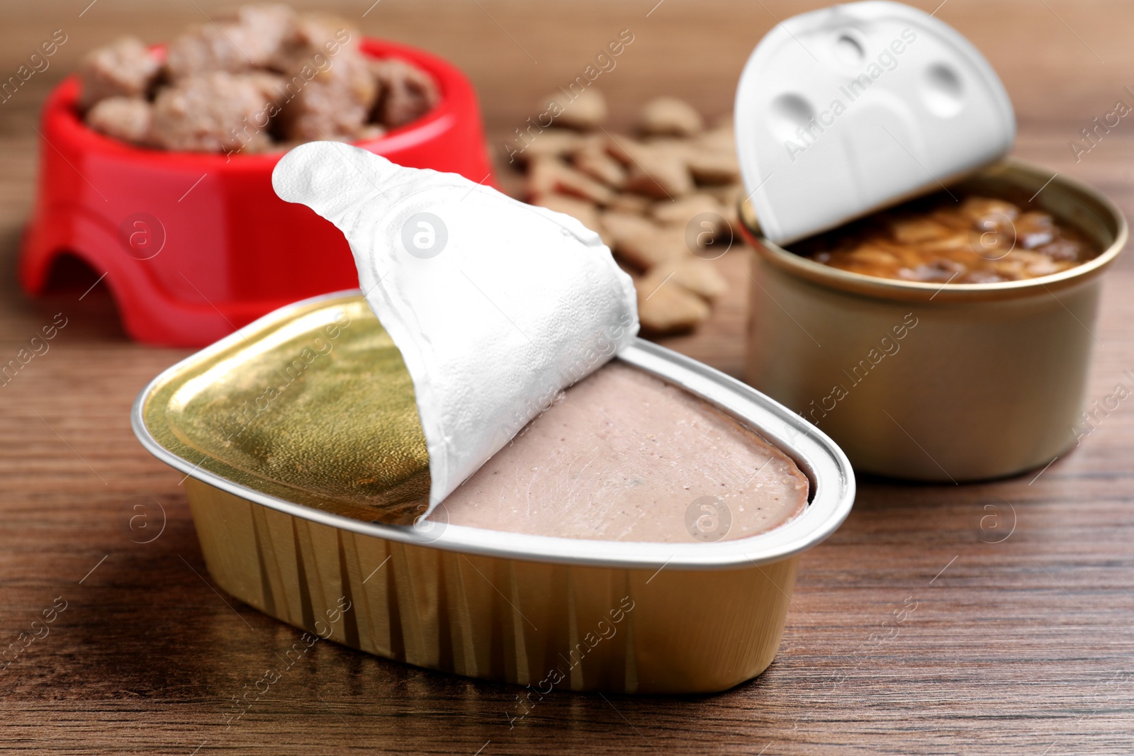 Photo of Open package of wet pet food on wooden table, closeup