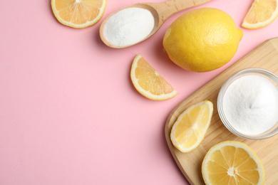 Photo of Baking soda and lemons on pink background, flat lay. Space for text