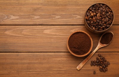 Photo of Coffee grounds and roasted beans on wooden table, flat lay. Space for text