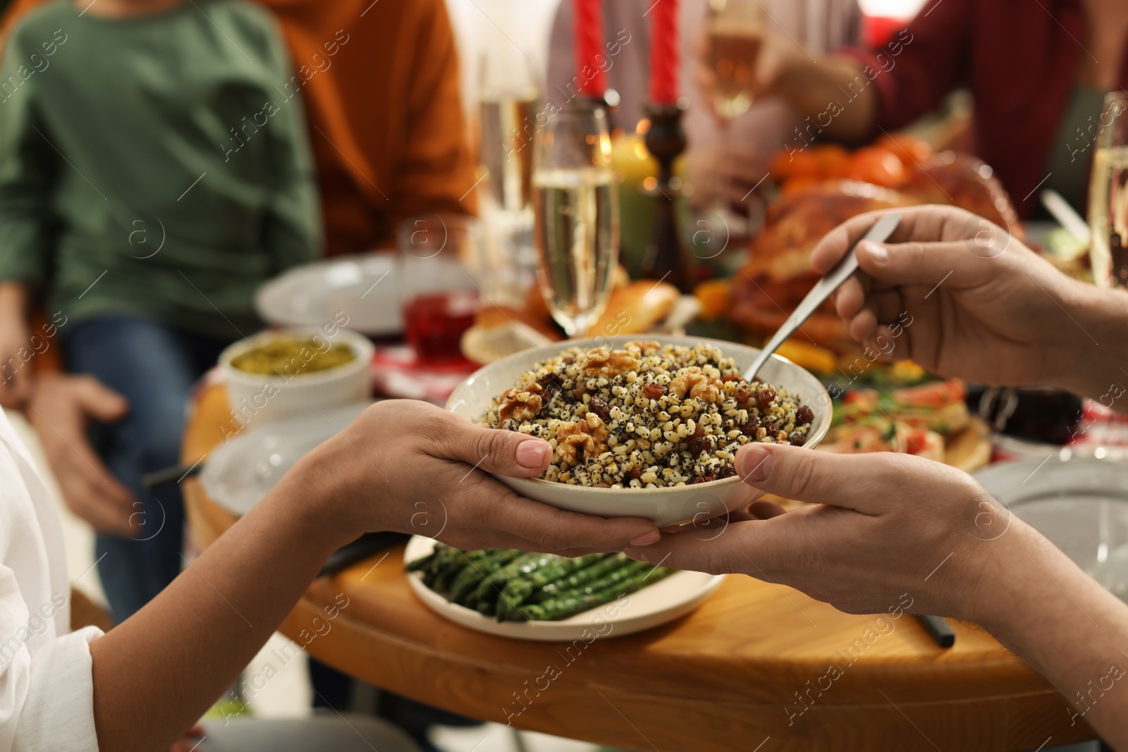 Photo of Woman giving bowl of traditional Christmas Slavic dish kutia to man at festive dinner, closeup