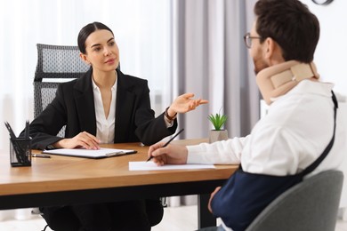 Injured man signing document in lawyer's office, selective focus