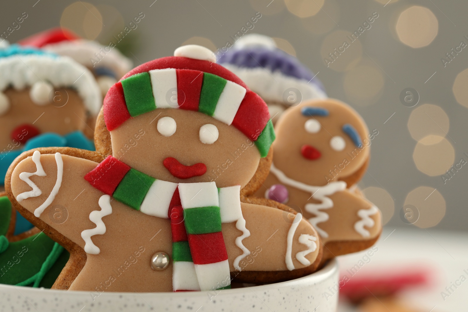 Photo of Delicious homemade Christmas cookies in bowl against blurred festive lights, closeup