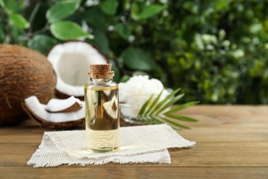 Photo of Bottle of organic coconut cooking oil on wooden table. Space for text