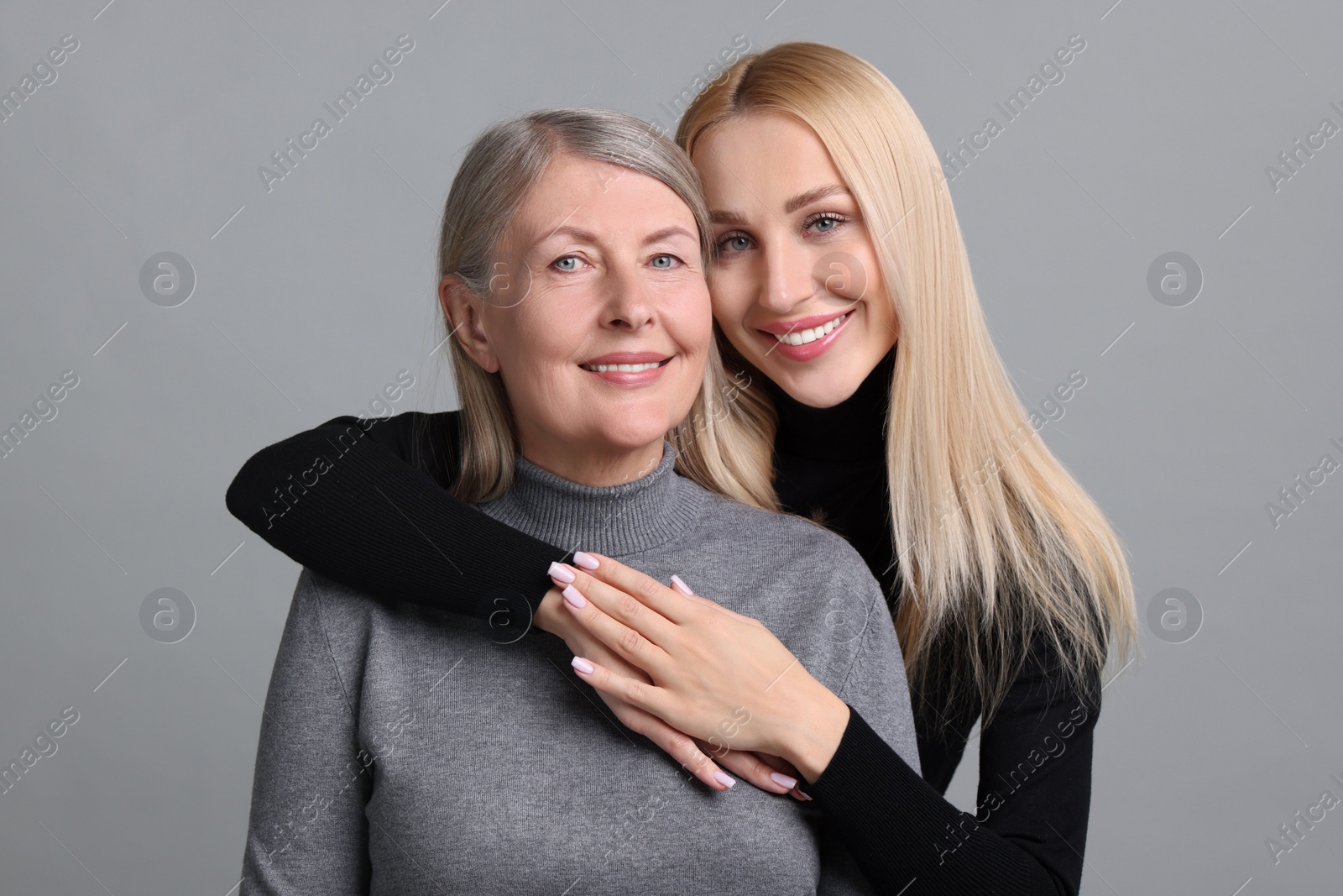 Photo of Family portrait of young woman and her mother on grey background