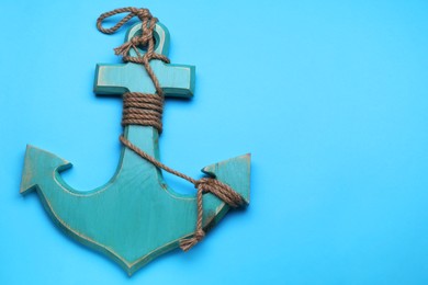 Photo of Wooden anchor figure on light blue background, top view. Space for text