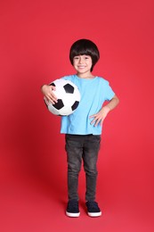 Cute little boy with soccer ball on red background