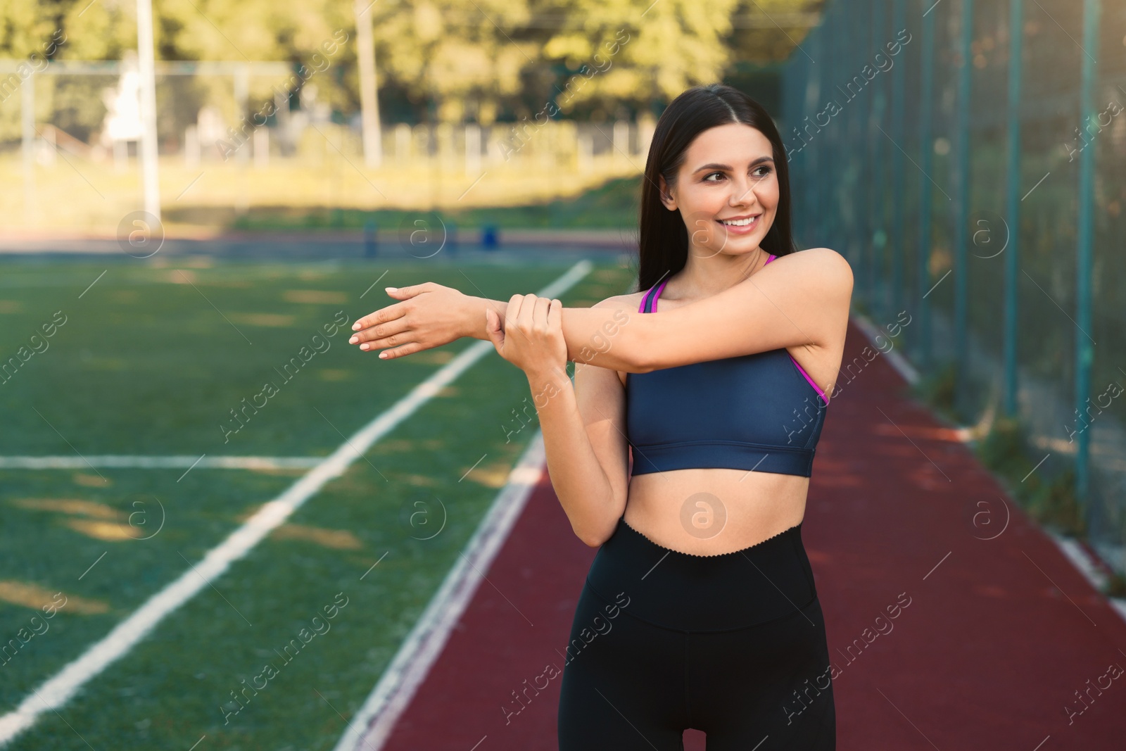 Photo of Smiling woman in sportswear stretching at game court. Space for text