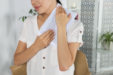 Young woman using heating pad on neck at home, closeup