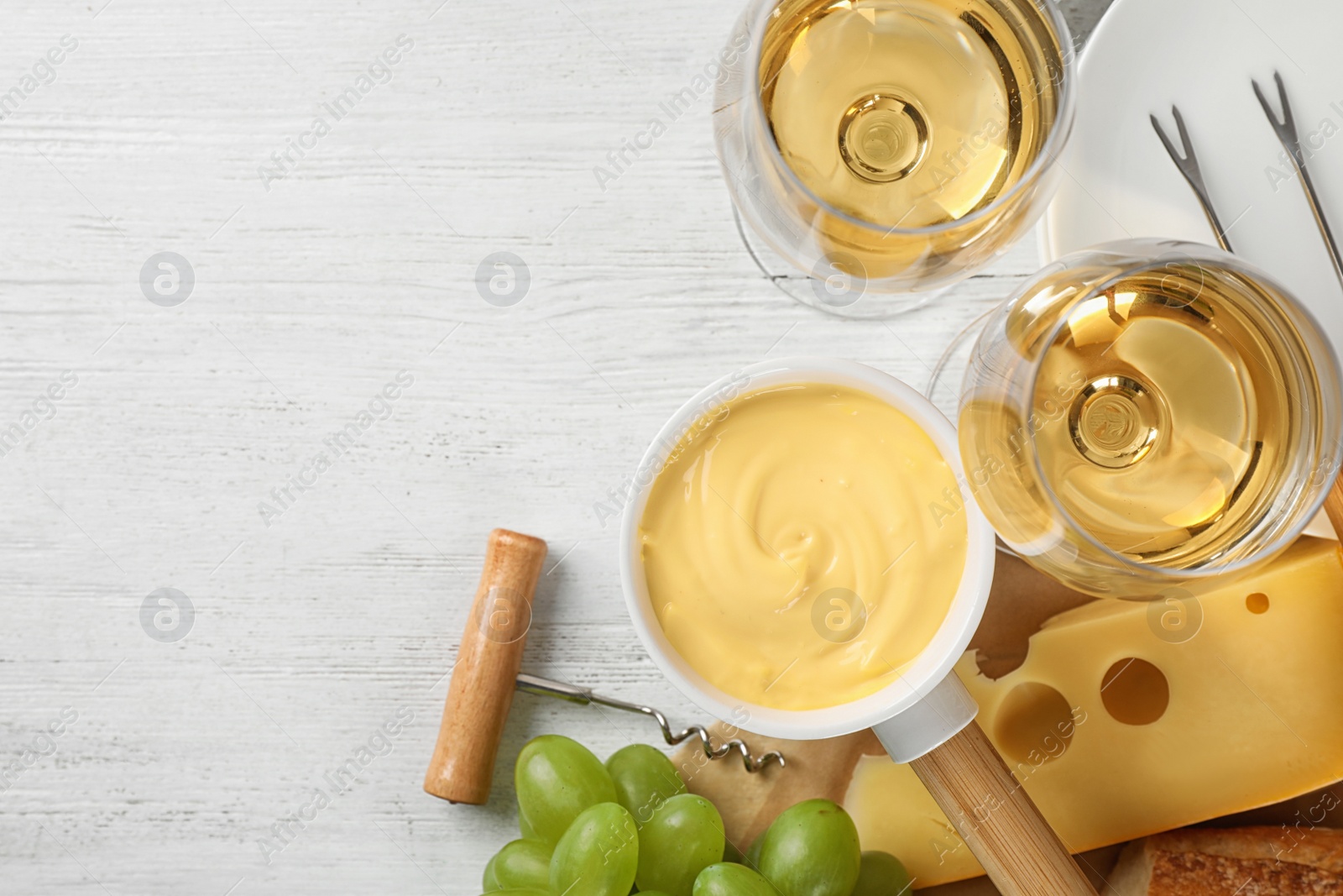 Photo of Flat lay composition with pot of tasty cheese fondue and products on white wooden table, space for text