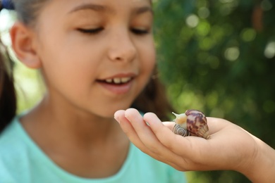 Photo of Kids playing with cute snails outdoors, focus on hand. Children spending time in nature