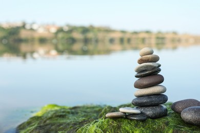 Photo of Stack of stones on seaweed near river, space for text. Harmony and balance concept