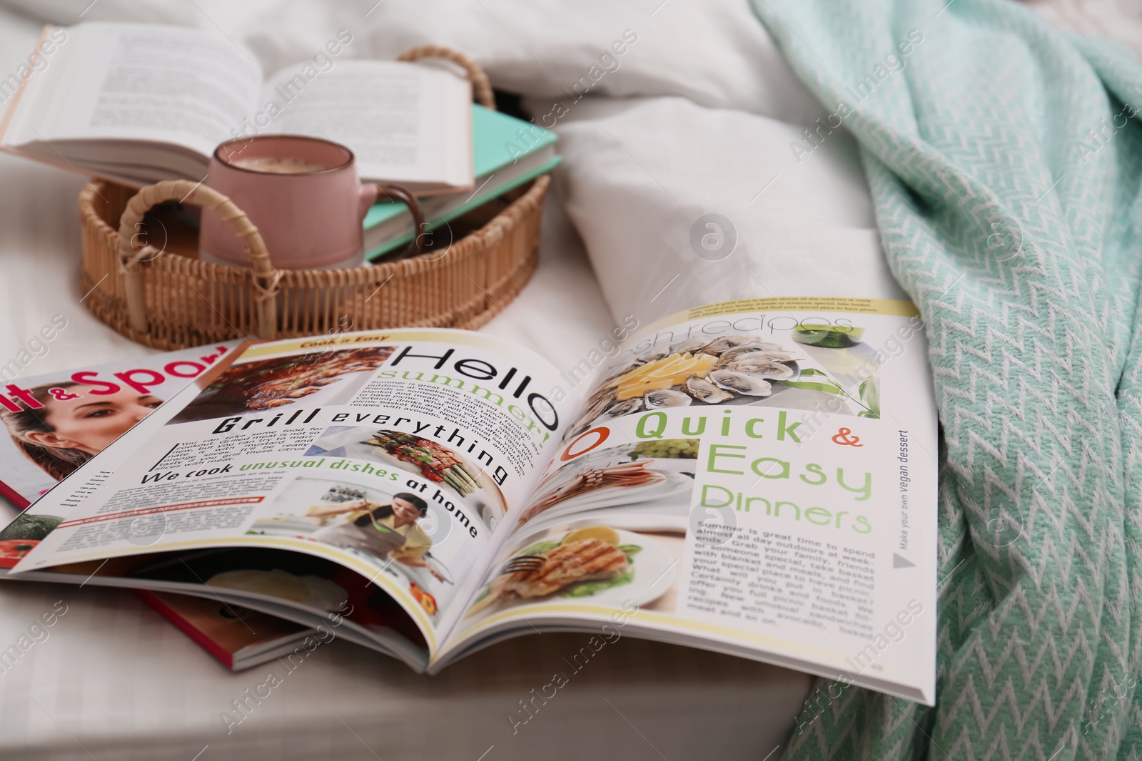 Photo of Different lifestyle magazines, books and coffee on bed