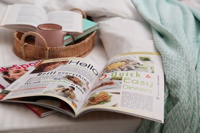 Photo of Different lifestyle magazines, books and coffee on bed