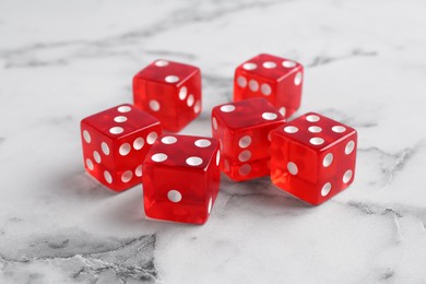 Photo of Many red game dices on white marble table, closeup