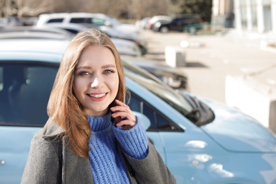 Portrait of beautiful young woman near parked cars on sunny day