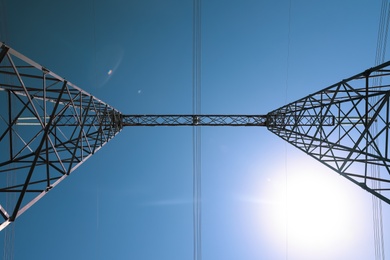 Photo of High voltage tower against blue sky, bottom view