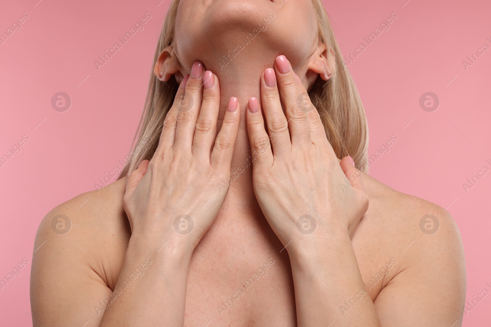 Photo of Woman touching her neck on pink background, closeup