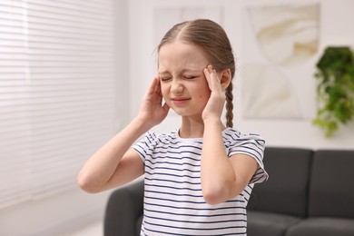 Photo of Little girl suffering from headache at home