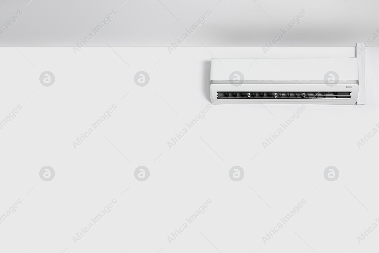 Photo of Modern air conditioner on white wall indoors