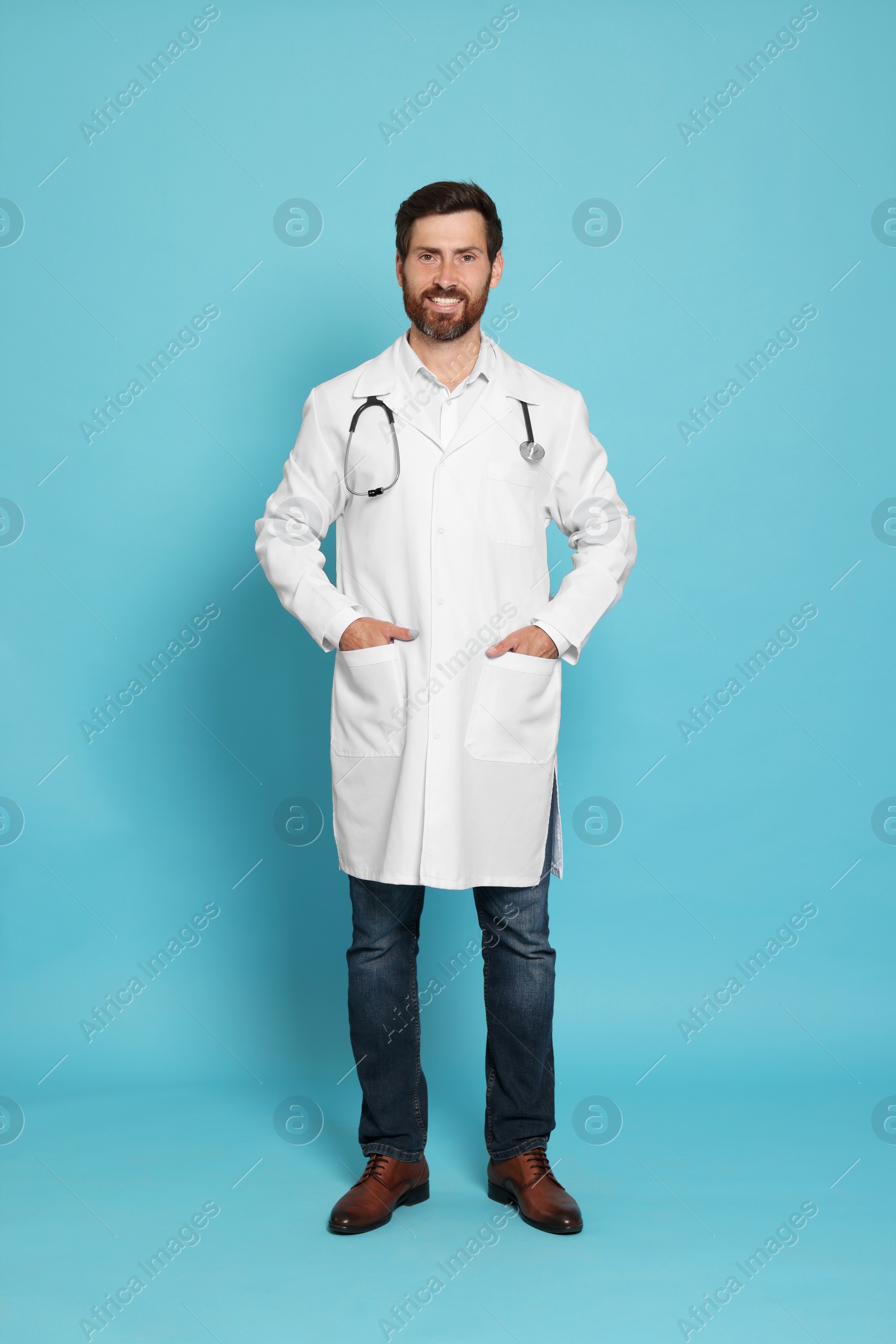 Photo of Full length portrait of doctor with stethoscope on light blue background